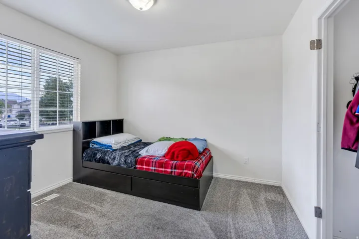 Carpeted bedroom with a single window, white walls, and a flush-mount ceiling light