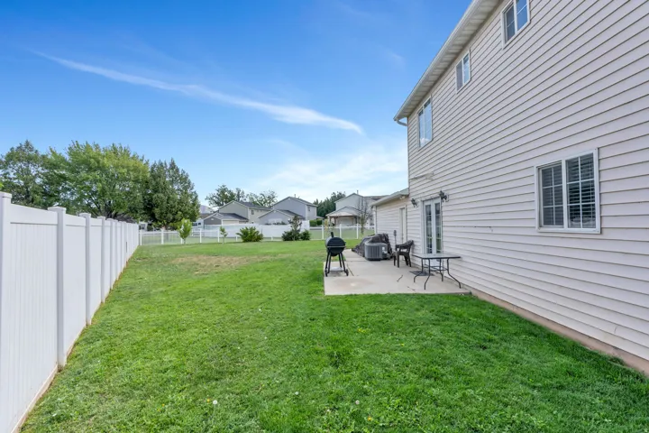 Expansive grass lawn with a white privacy fence