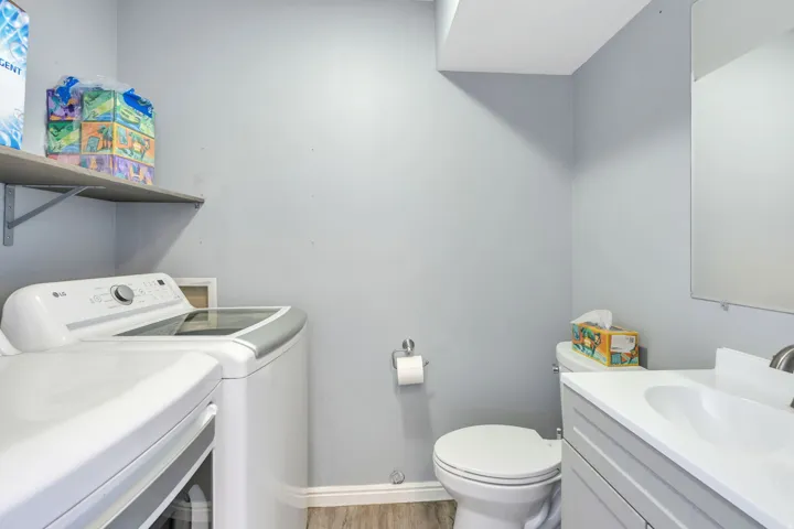 Built-in shelving, wood-finish flooring, wall-mounted mirror, and vanity with integrated sink