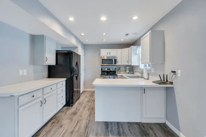 Kitchen with light gray cabinetry, light countertops, stainless steel appliances, and wood-finish flooring