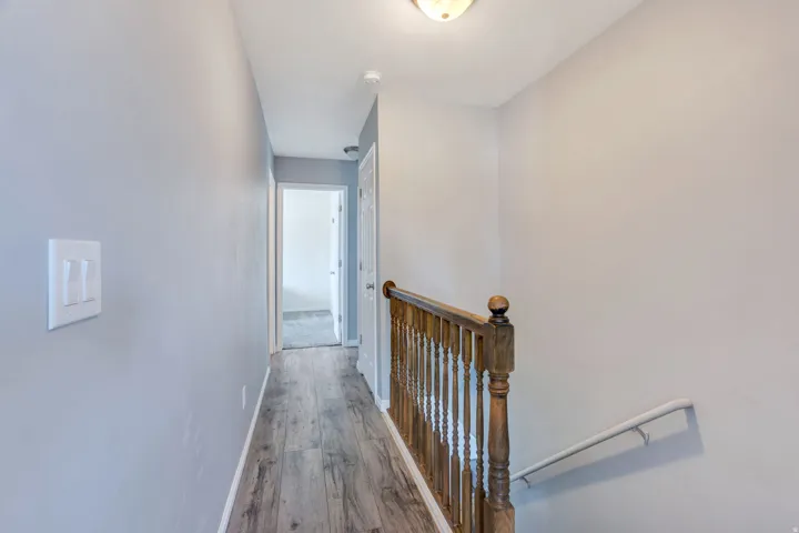 Wood-finish flooring leading to a hallway with a white ceiling and flush mount lighting