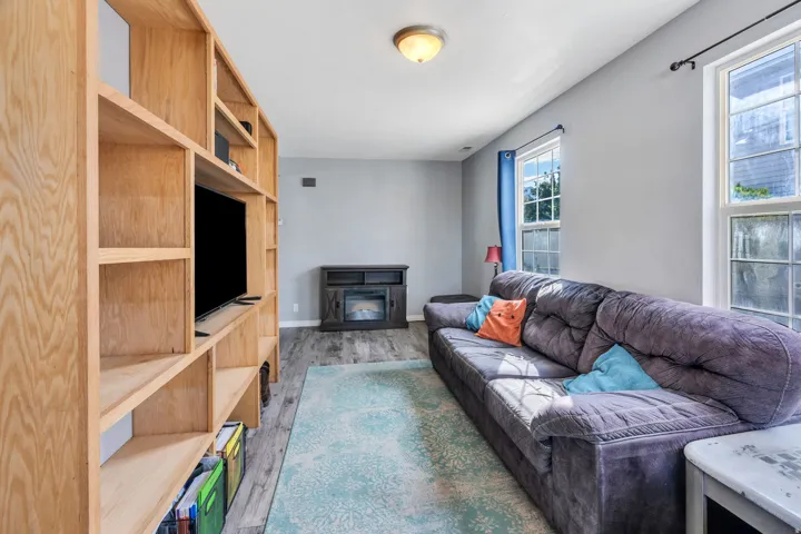 Living area featuring wood-finish flooring, light gray wall paint, and a built-in wood shelving unit