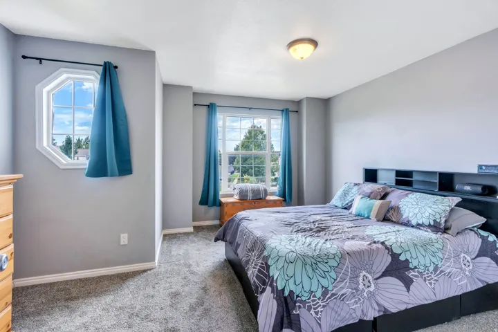 Recessed octagonal window, additional rectangular window, built-in headboard storage, flush-mount ceiling light, and gray wall paint