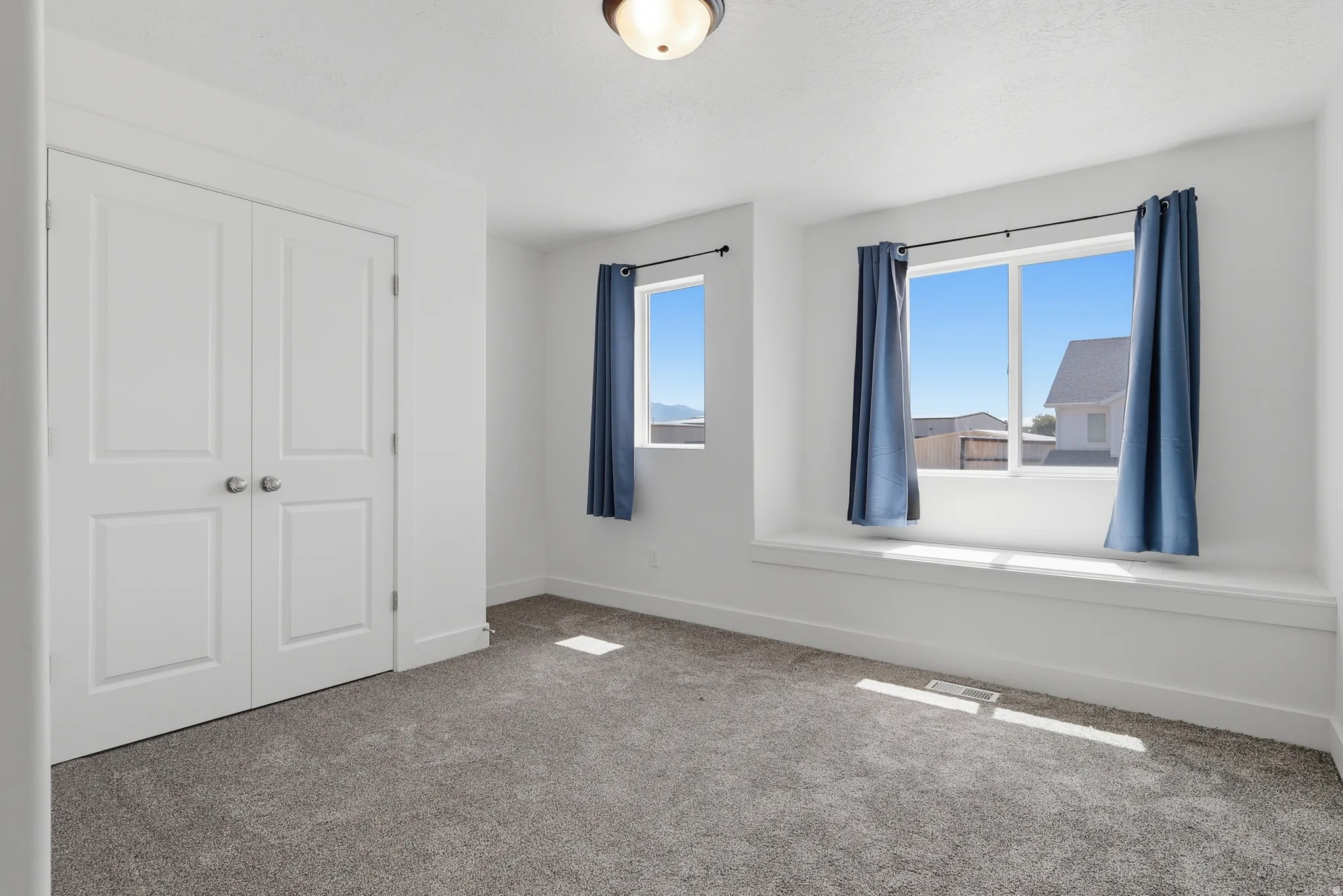 Recessed lighting fixture, dual windows with a window seat, white trim, and gray carpet flooring