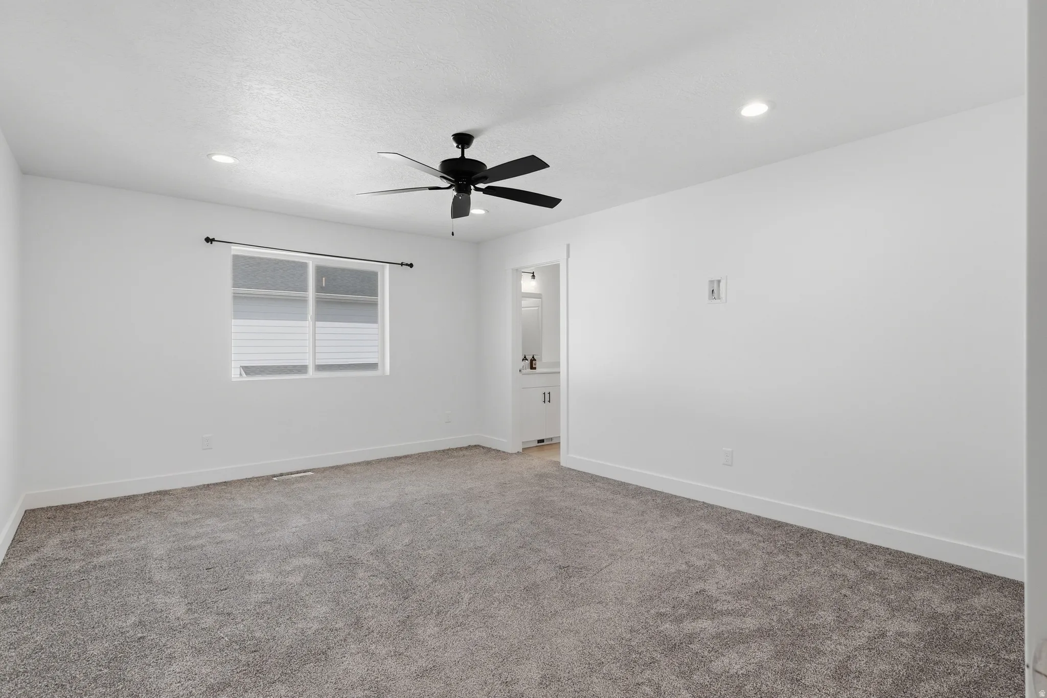 Spacious room with gray carpet flooring, white walls, a black ceiling fan, recessed lighting, and a white framed window
