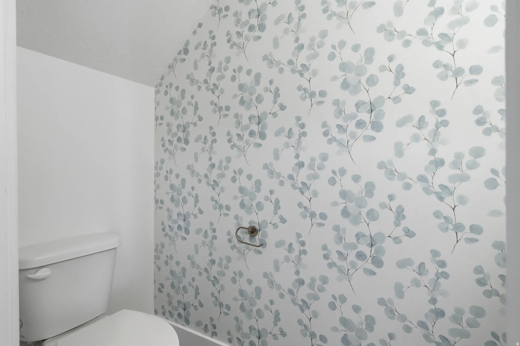 White toilet with a patterned accent wall and a wall-mounted towel holder