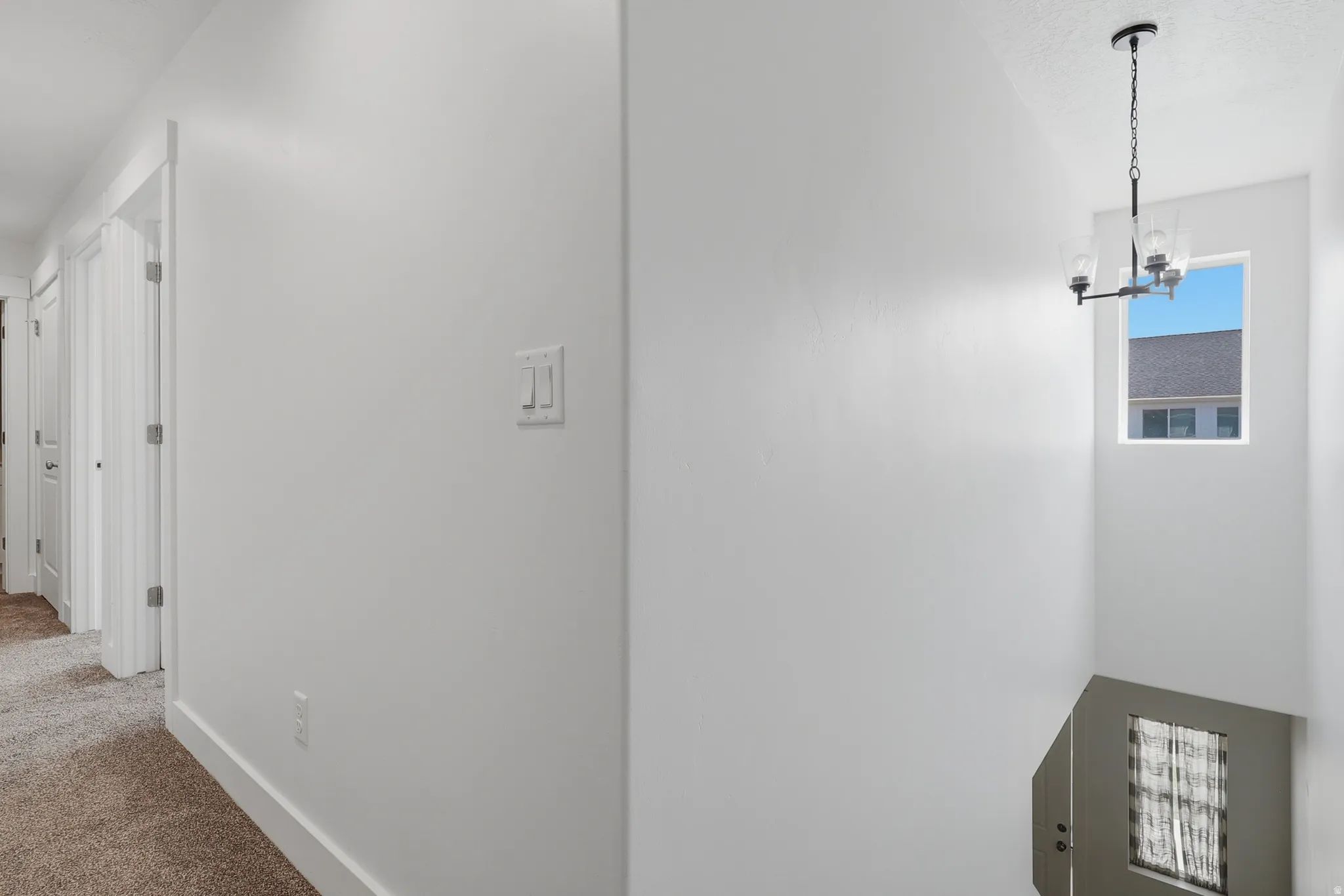 White interior walls, recessed lighting, carpet flooring, baseboard trim, and a contemporary chandelier