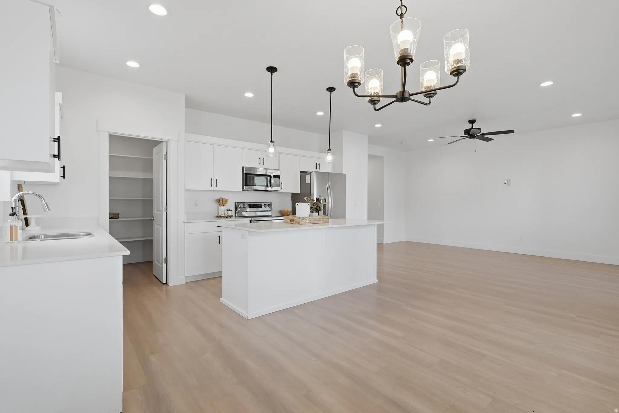 Open-concept kitchen with a center island, stainless steel appliances, and wood-finish flooring