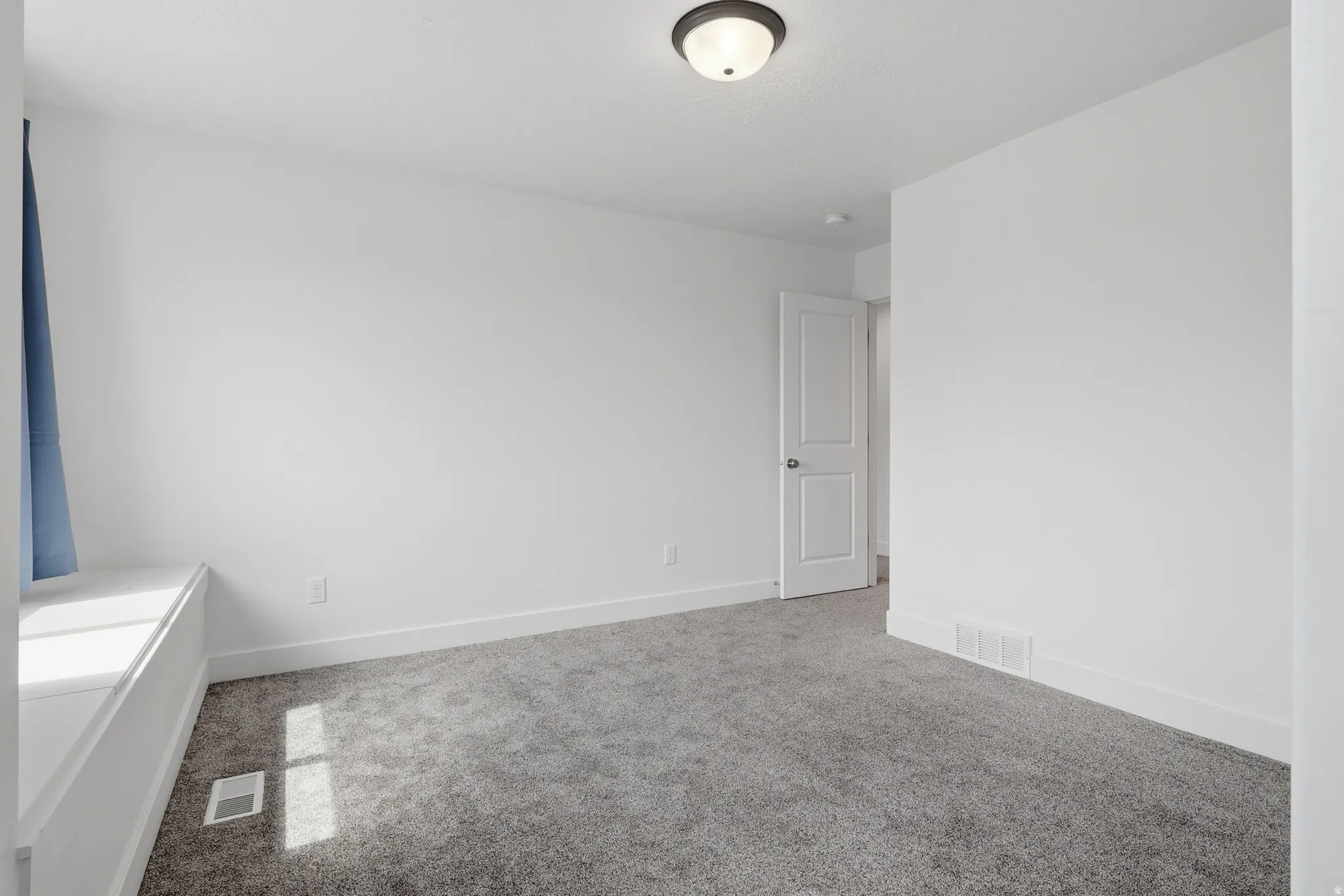 Carpeted room featuring a ceiling-mounted light fixture, white walls, and a window bench