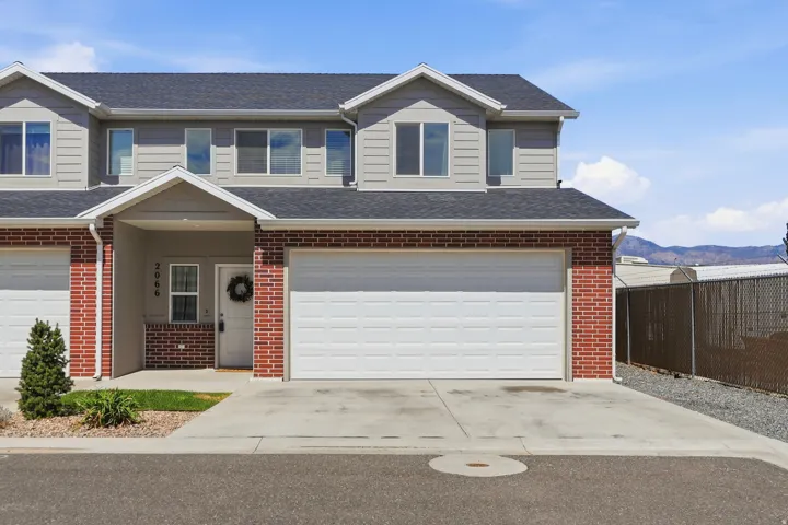 Two-story townhouse featuring a brick and siding exterior, an attached garage with a white garage door, a covered entryway, and a concrete driveway