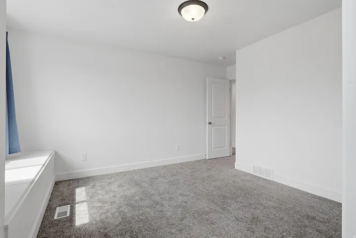 Carpeted room featuring a ceiling-mounted light fixture, white walls, and a window bench