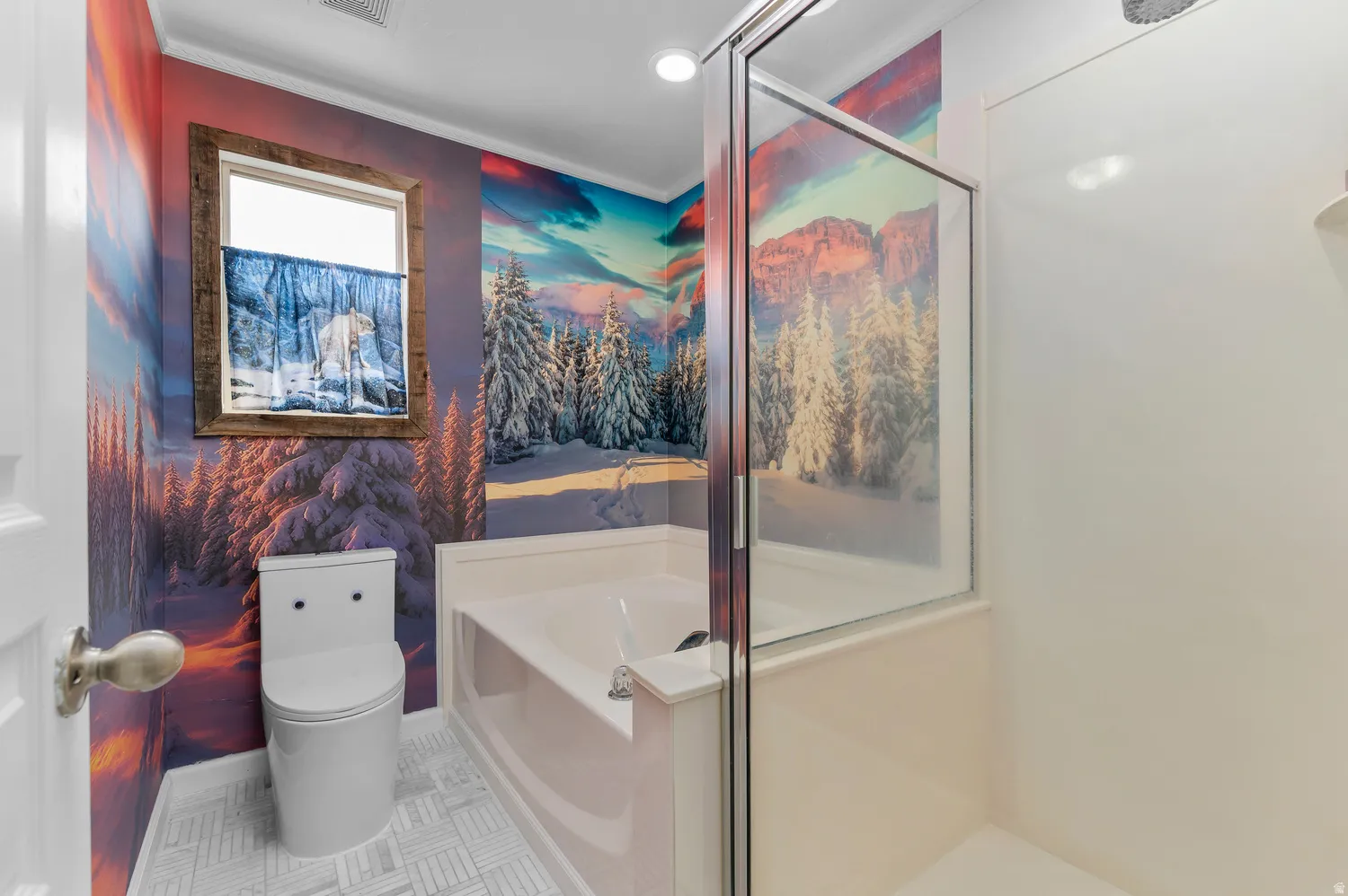 Built-in bathtub, glass-enclosed shower, window with wood-finish trim, modern toilet, and patterned wall covering