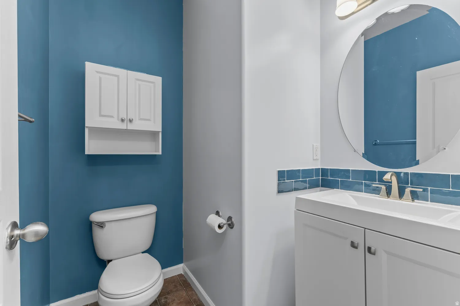 White vanity with integrated sink, brushed nickel faucet, and round mirror