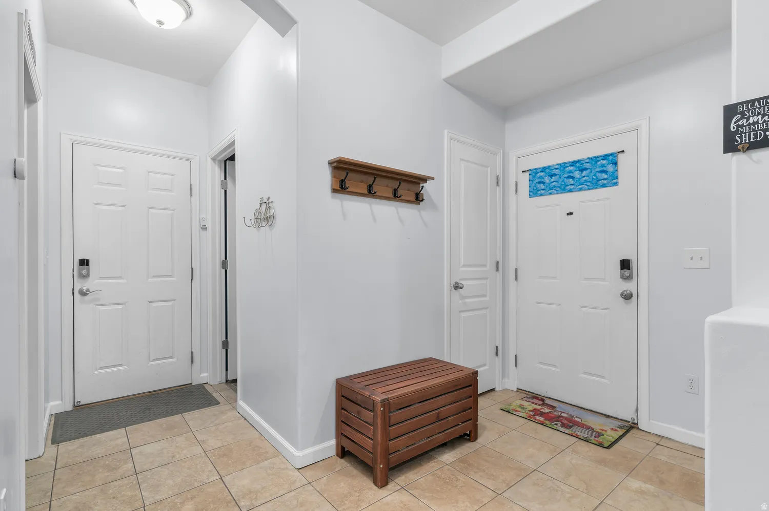 Tile flooring, white paneled doors, wall-mounted coat rack, recessed ceiling light
