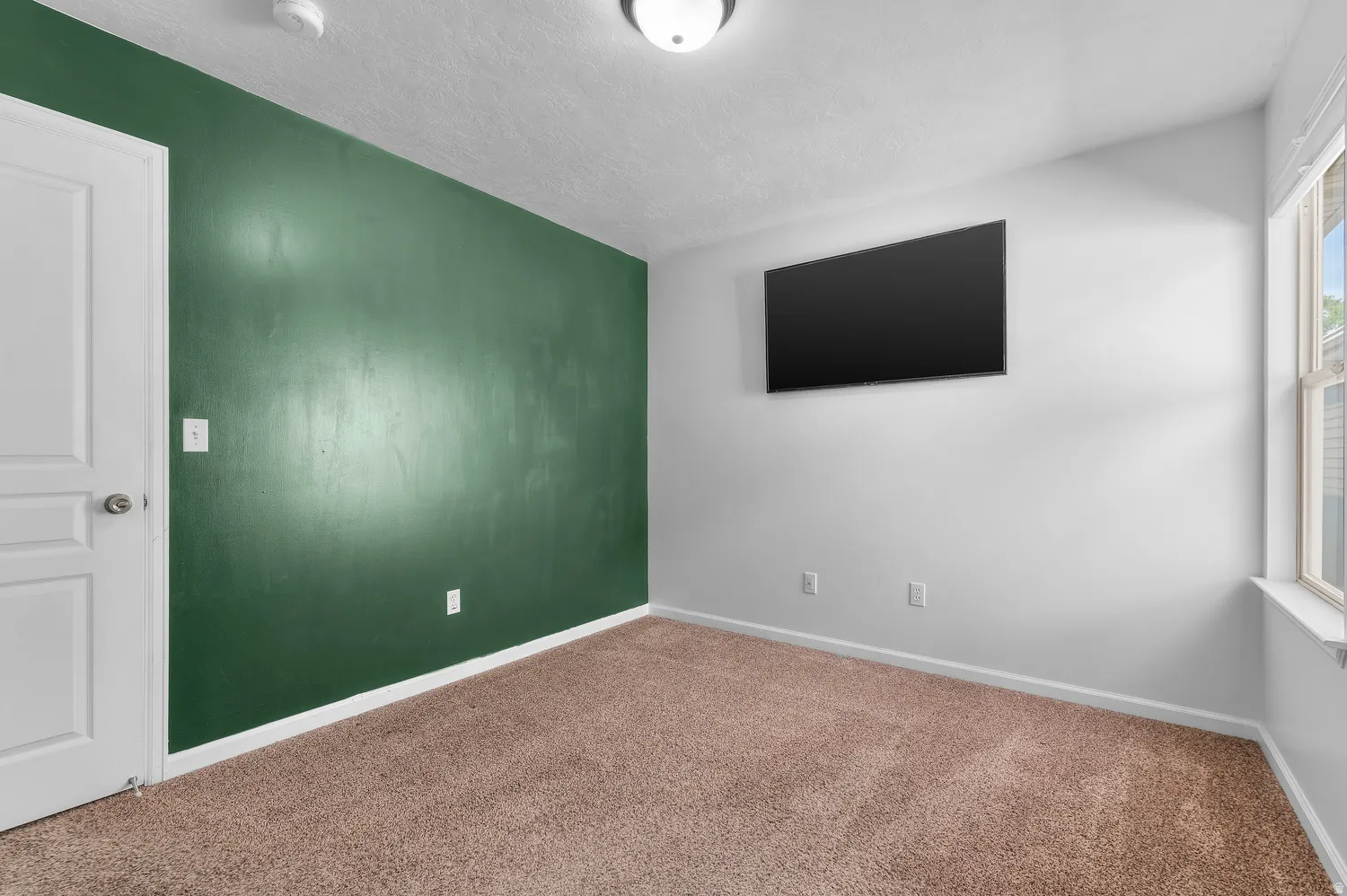 Room featuring a dark green accent wall, light-colored walls, and carpeting