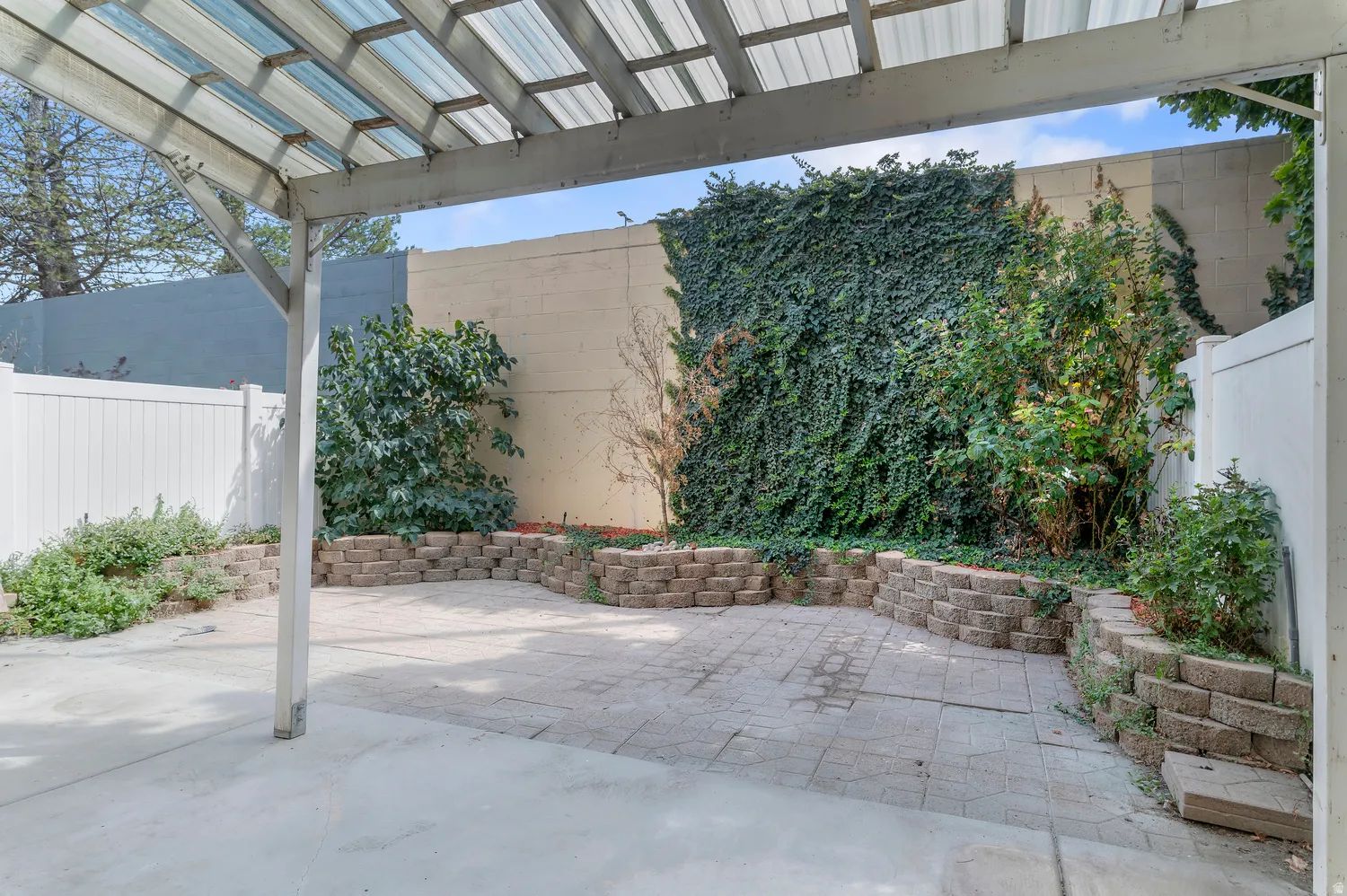 Patio with a translucent covered pergola, paver and concrete flooring, and raised garden beds