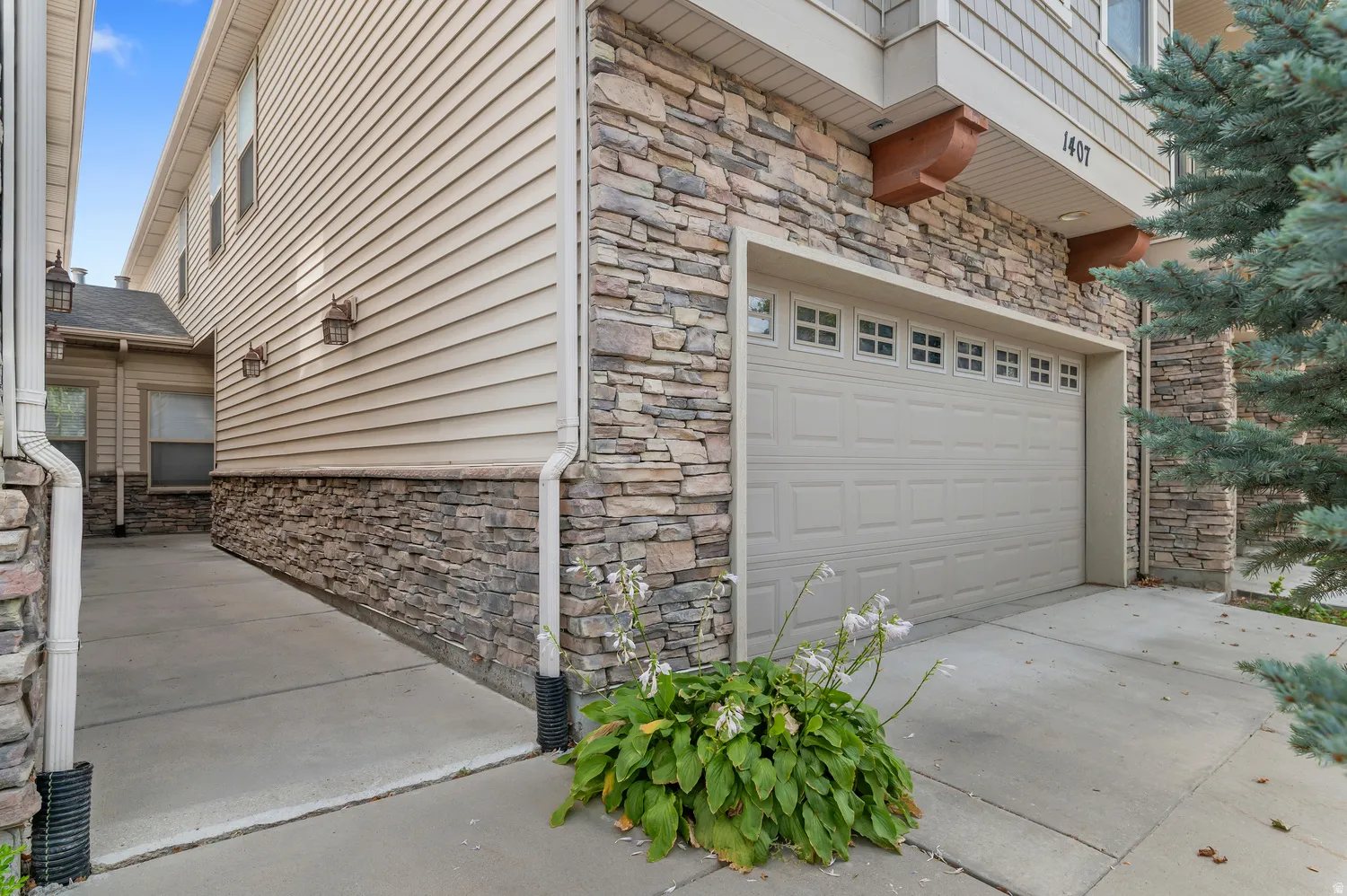 Stone and siding exterior with a two-car garage featuring paneled doors and multiple windows