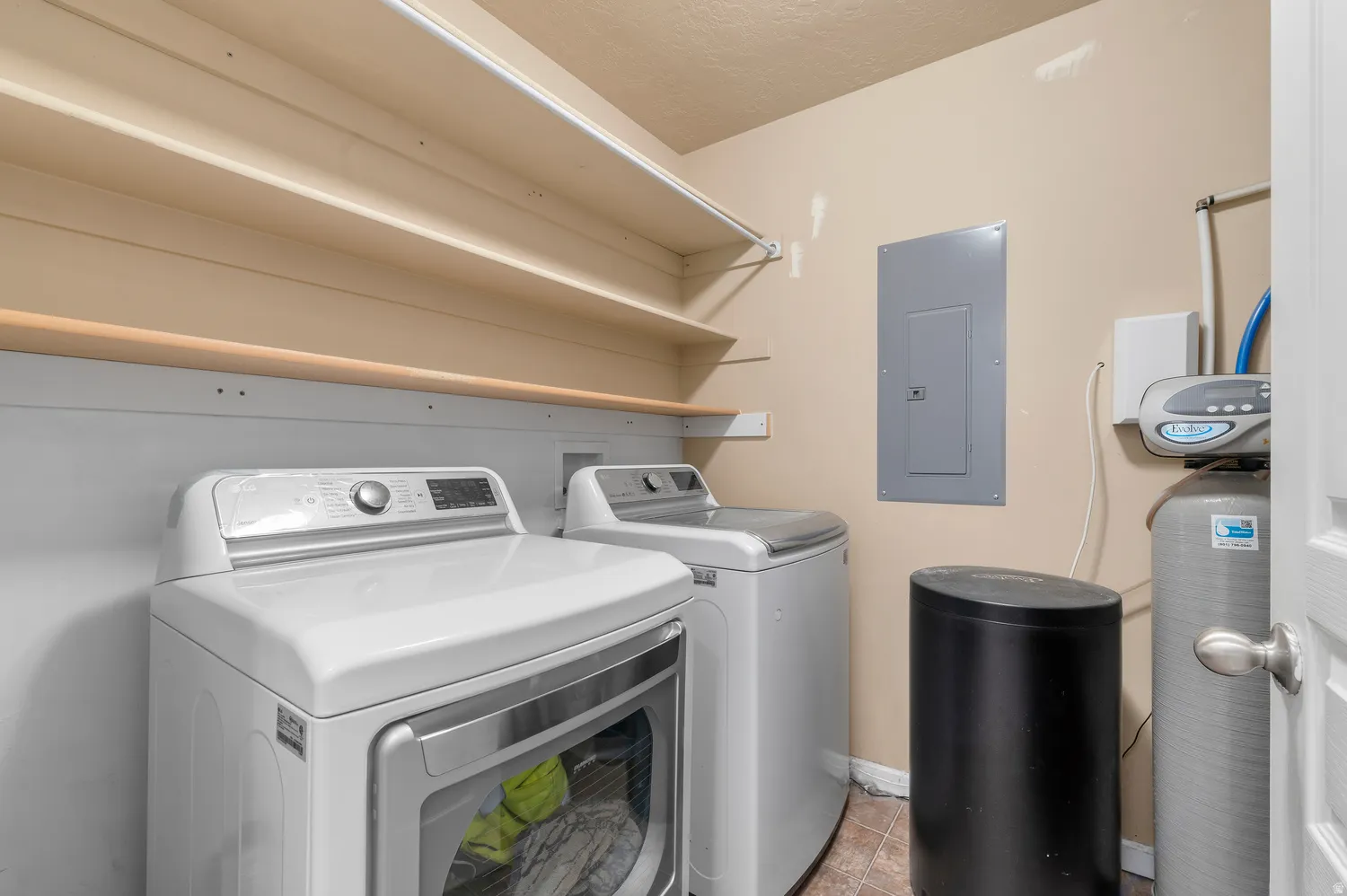 Dedicated utility area featuring integrated shelving, tile flooring, and essential mechanical equipment