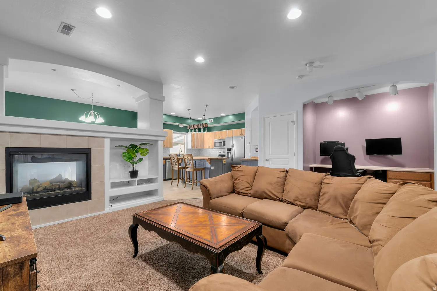 Built-in fireplace with a tiled surround, recessed lighting, and an arched entryway