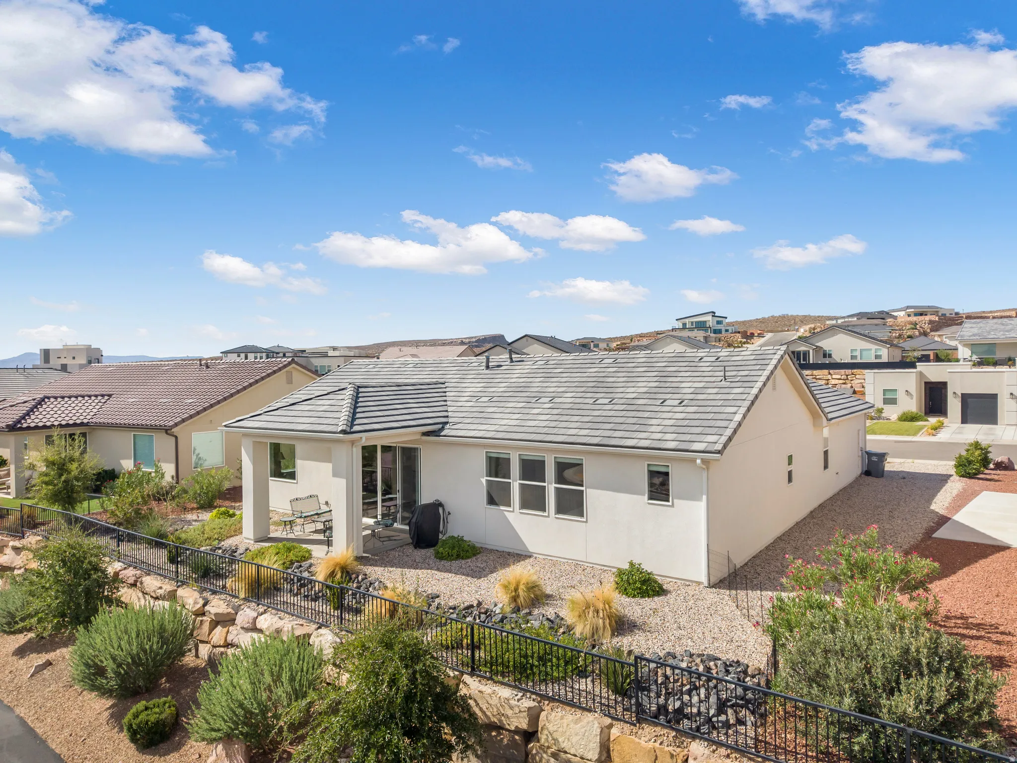 Rear exterior featuring a covered patio, multiple large windows, and a tiled roof