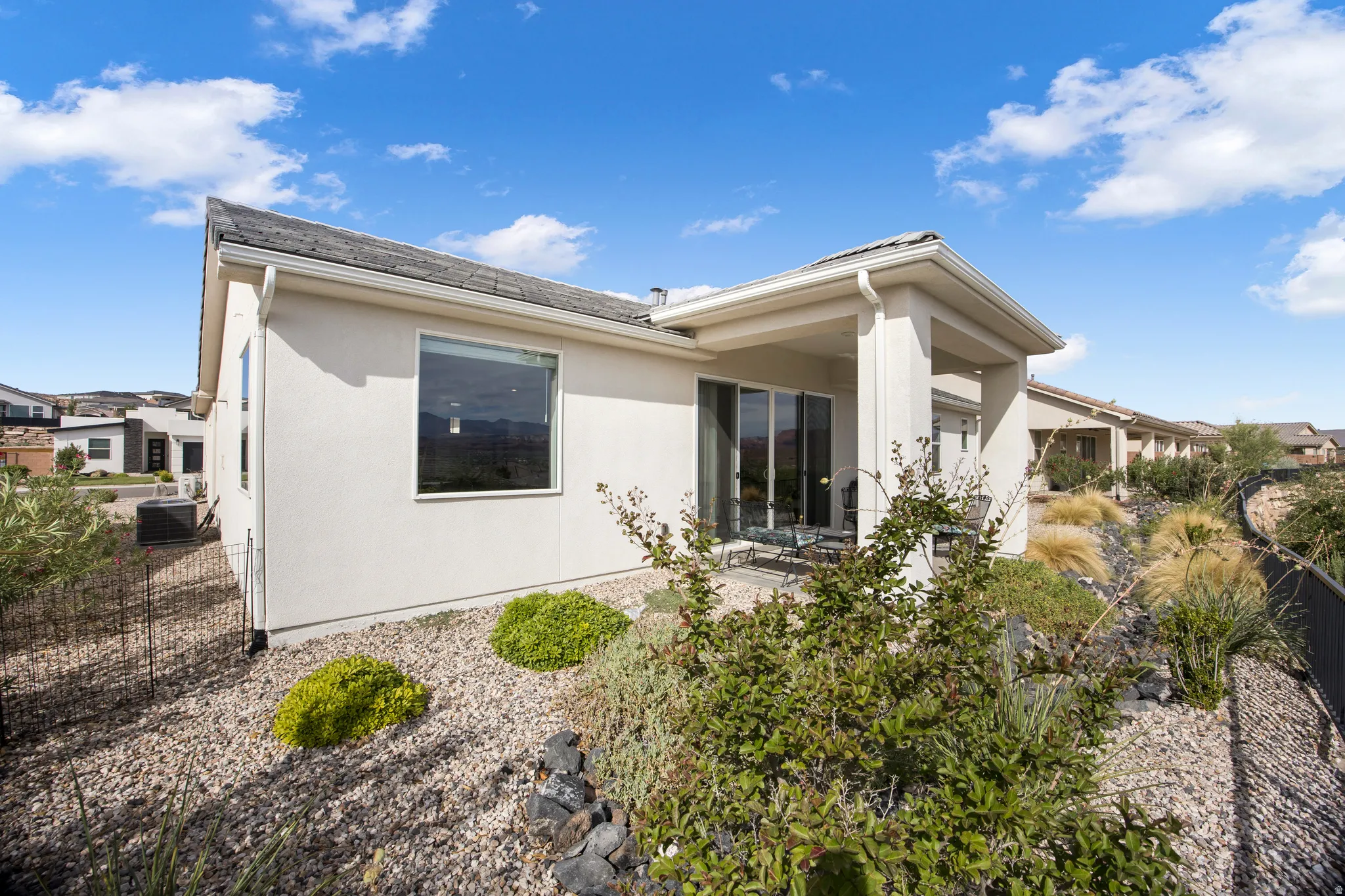 Stucco exterior with a covered patio, sliding glass doors, and a large picture window