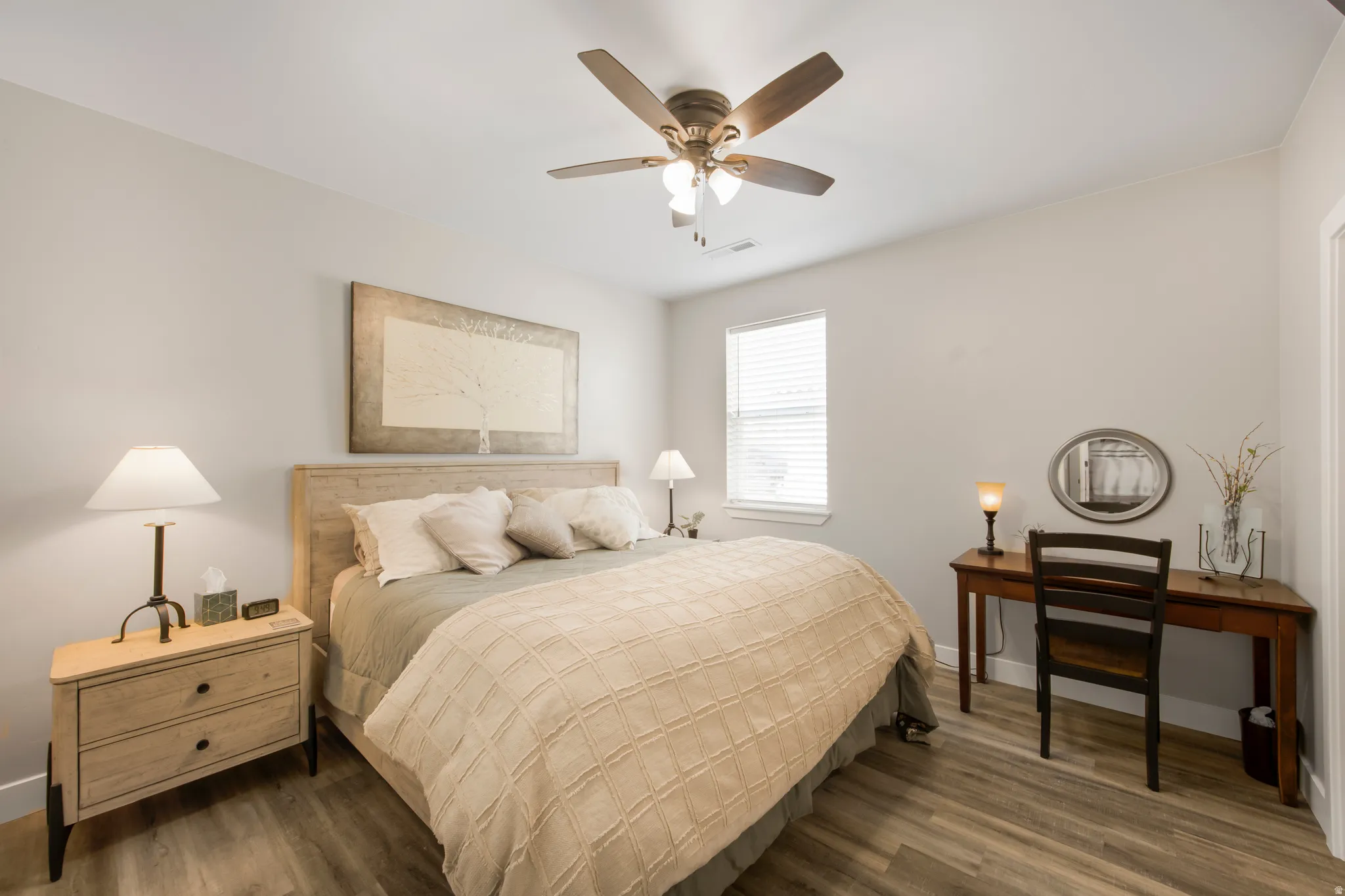 Neutral wall paint, wood-finish flooring, ceiling fan with integrated lighting, window with blinds, and a solid-core door