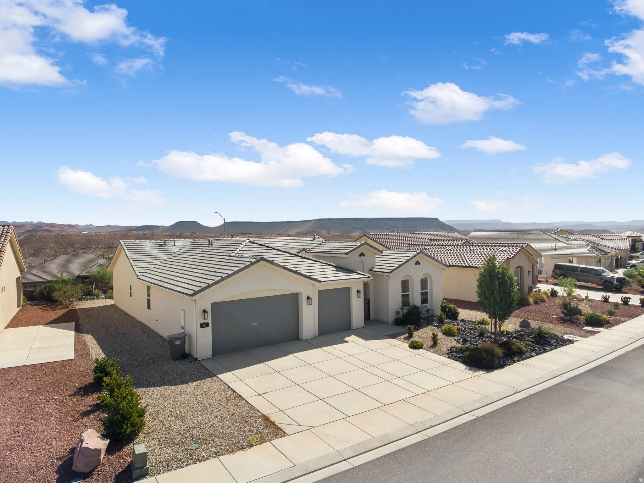 Contemporary stucco exterior with a tiled roof, multi-car garage, and a concrete driveway