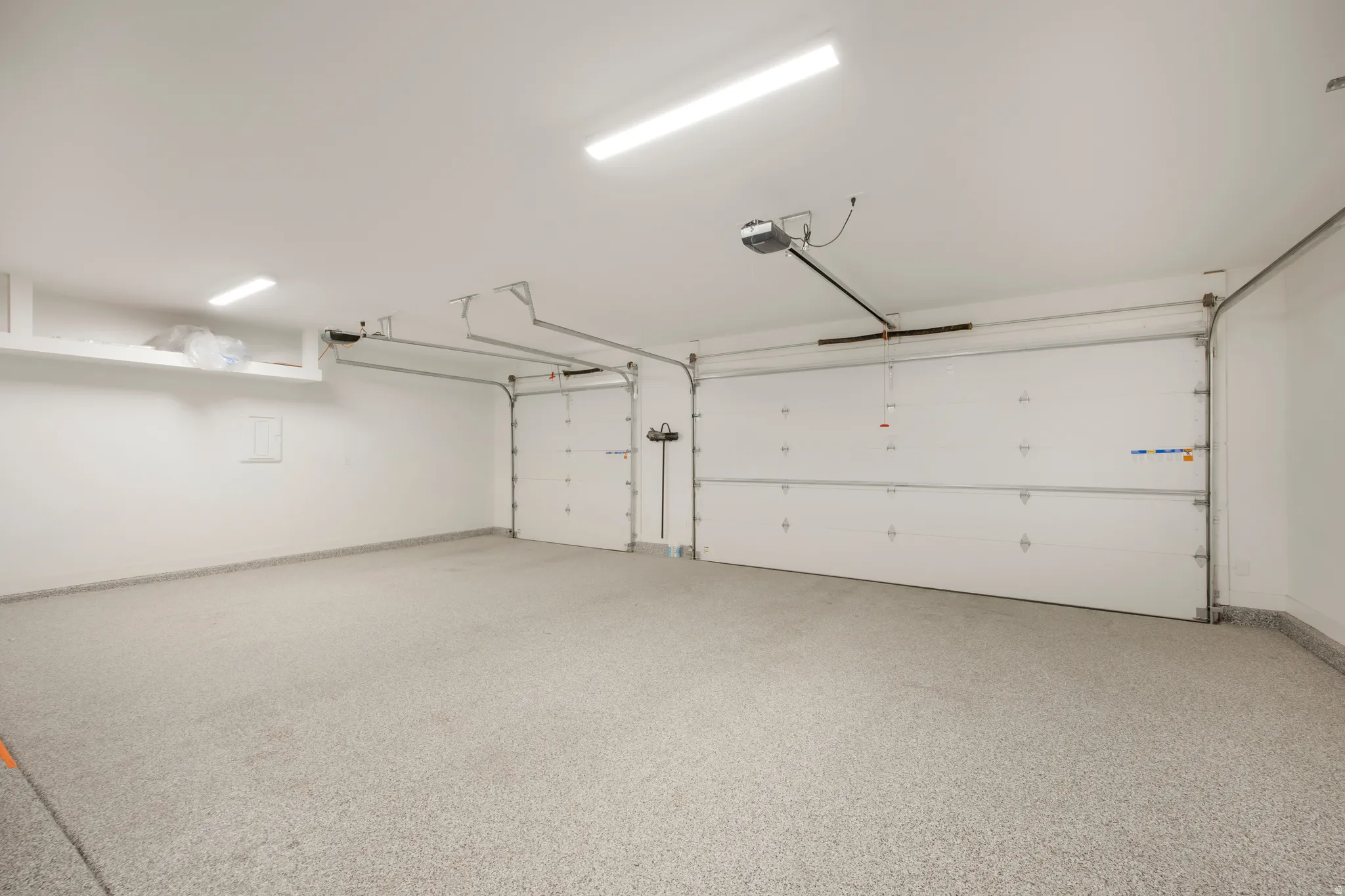 Two-car garage with white paneled doors, automatic door openers, and track lighting