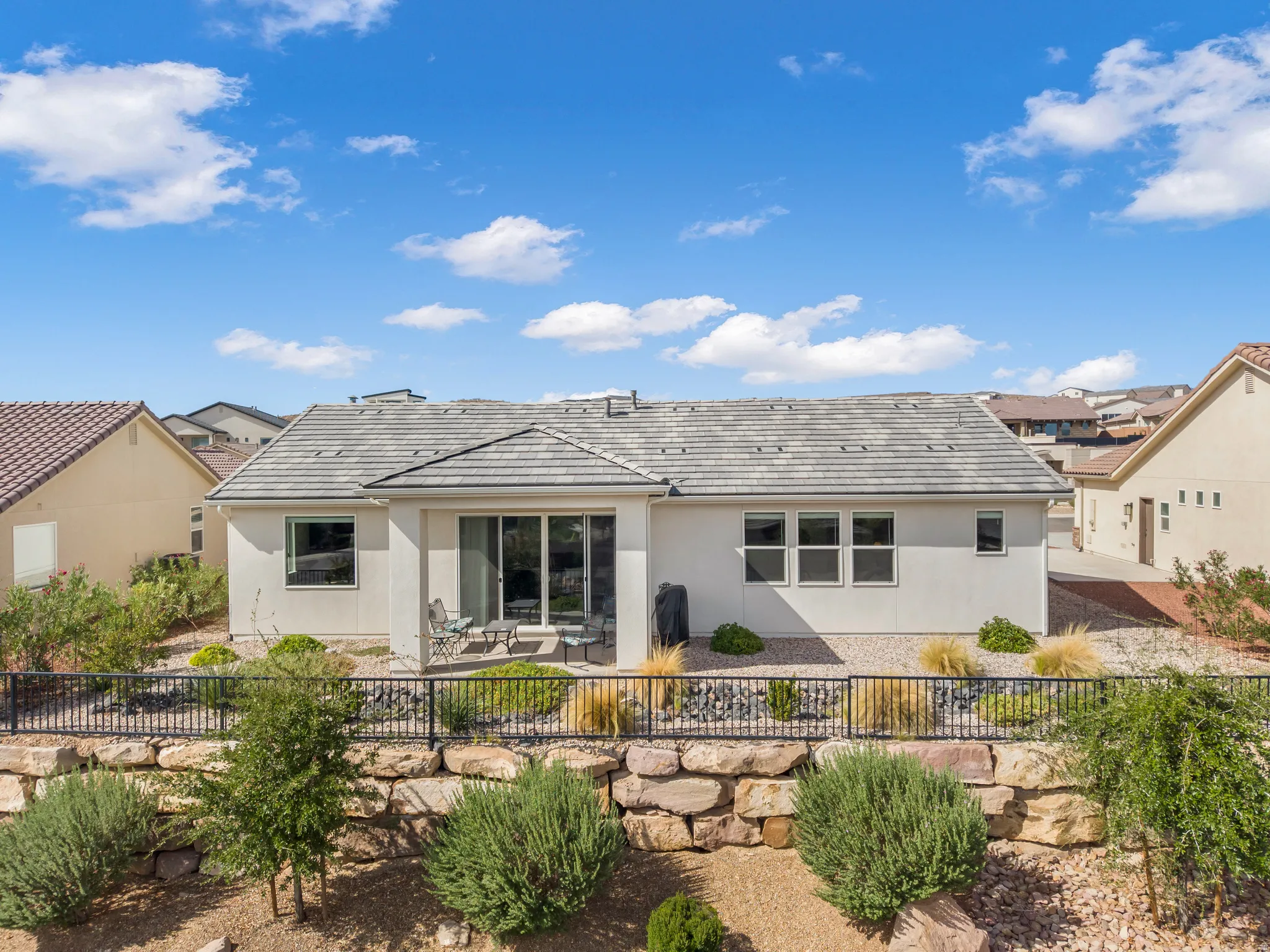 Rear exterior featuring a tiled roof, stucco siding, and multiple windows