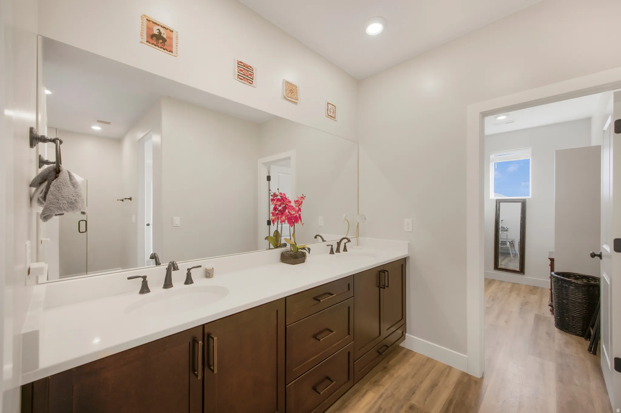 Spa-inspired primary bathroom featuring a lengthy dual-sink vanity with wood cabinetry, white quartz countertops, and oil-rubbed bronze faucetry