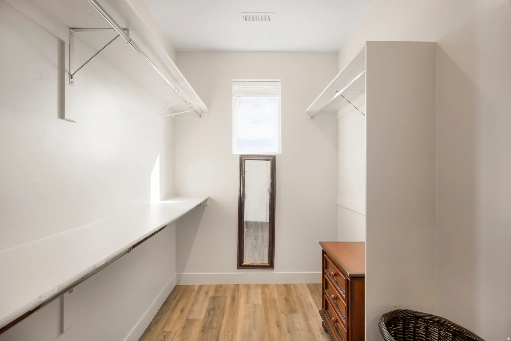 Recessed window, wood-finish flooring, built-in shelving, and hanging rods