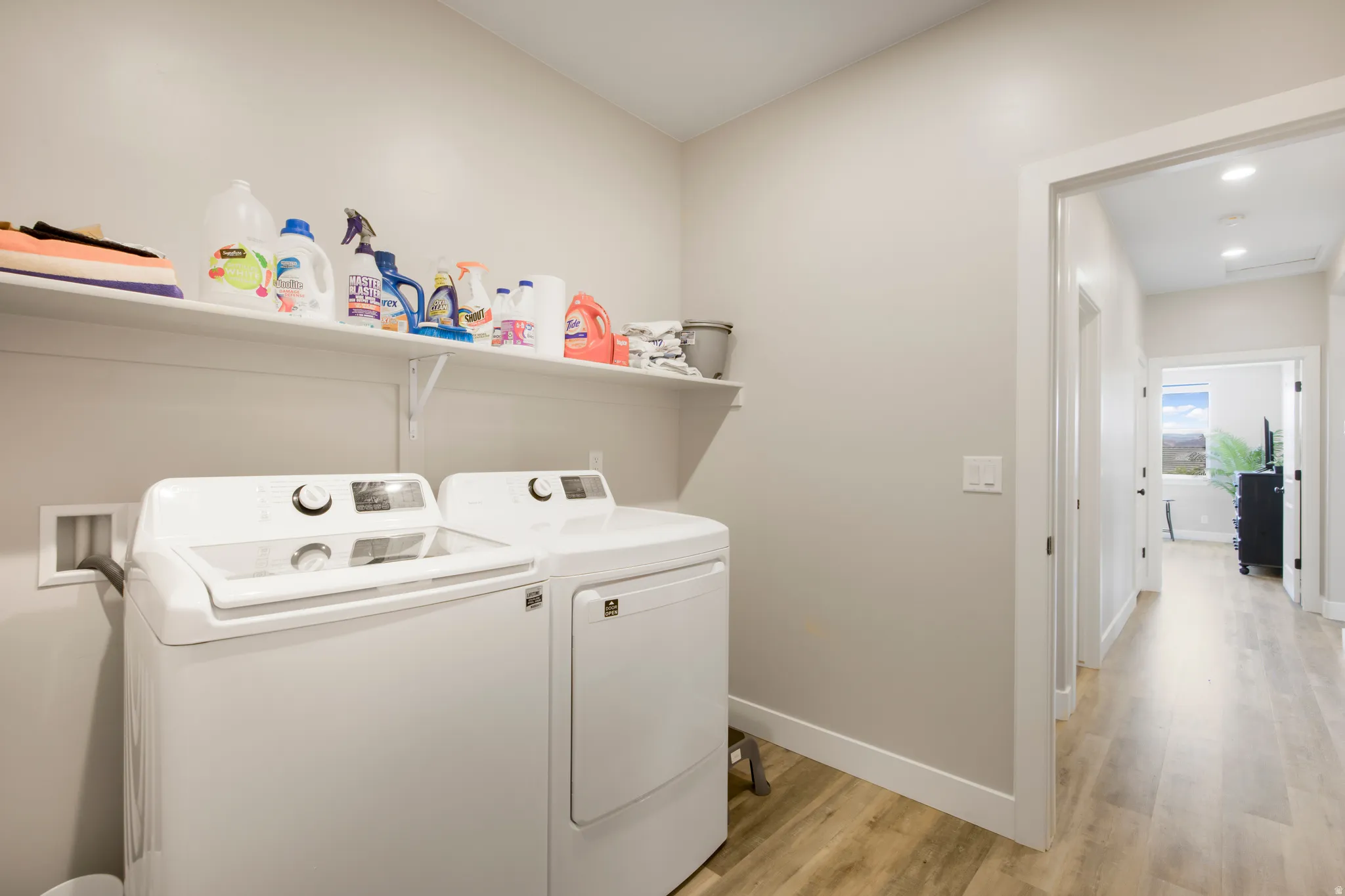 Dedicated laundry area with durable wood-finish flooring and convenient wall shelving