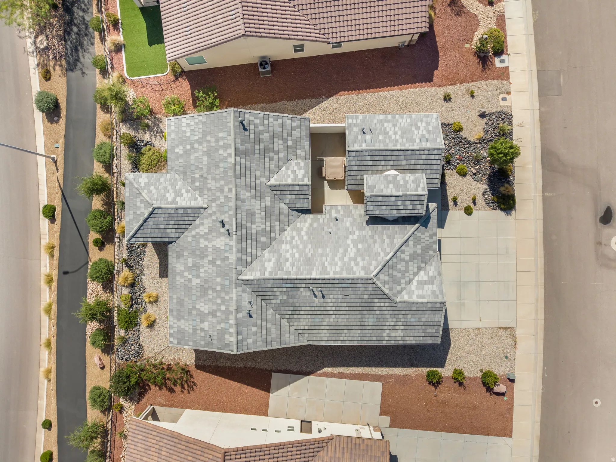 Property with a multi-level roofline, a paved driveway, and varied landscaping featuring decorative rock and shrubbery