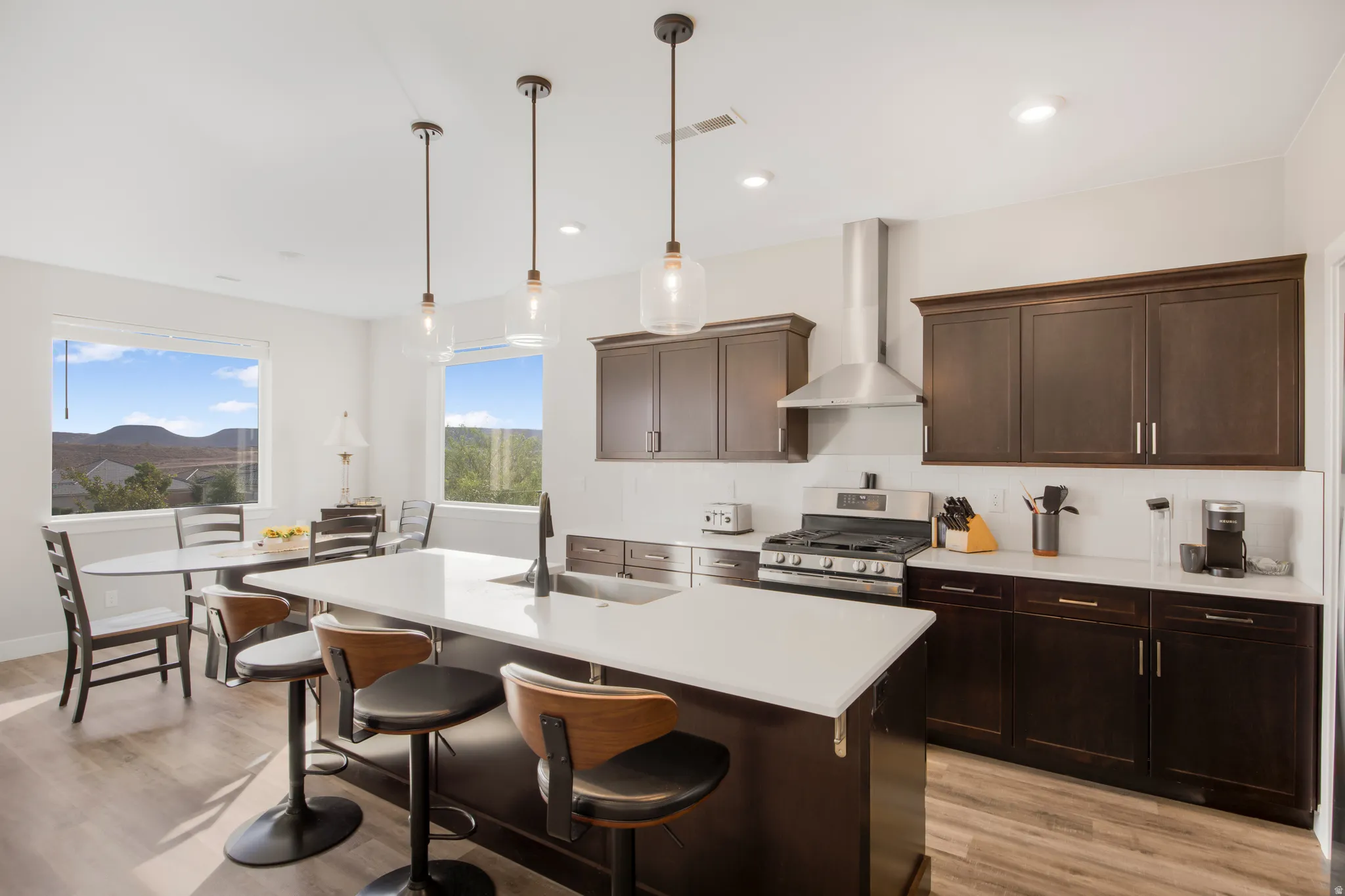 Open-concept kitchen featuring dark wood cabinetry, stainless steel appliances, a center island with seating, and wood-finish flooring
