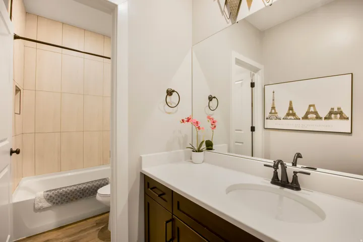 Bathroom featuring a single vanity with a white countertop, dark wood-finish cabinetry, an undermount sink, and a black faucet