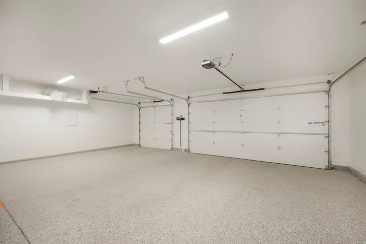 Two-car garage with white paneled doors, automatic door openers, and track lighting