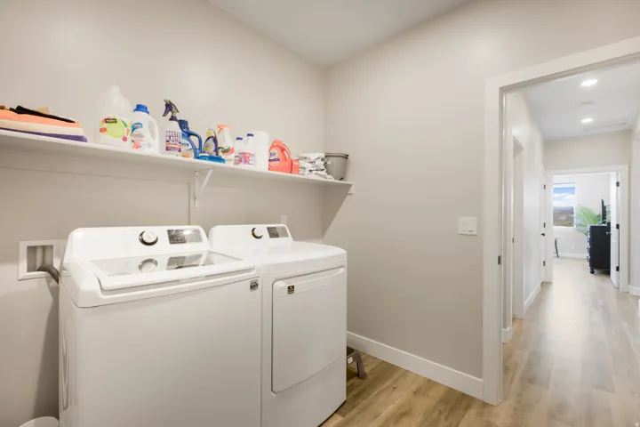 Dedicated laundry area with durable wood-finish flooring and convenient wall shelving