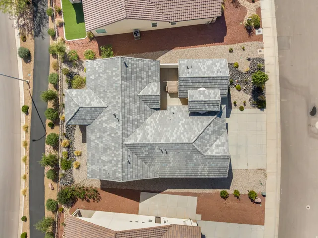 Property with a multi-level roofline, a paved driveway, and varied landscaping featuring decorative rock and shrubbery