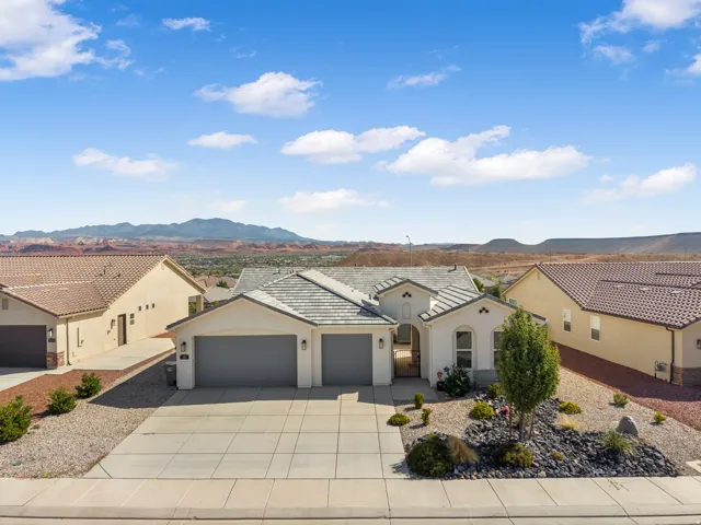Contemporary stucco exterior with a tiled roof, two-car garage, and desert-inspired landscaping