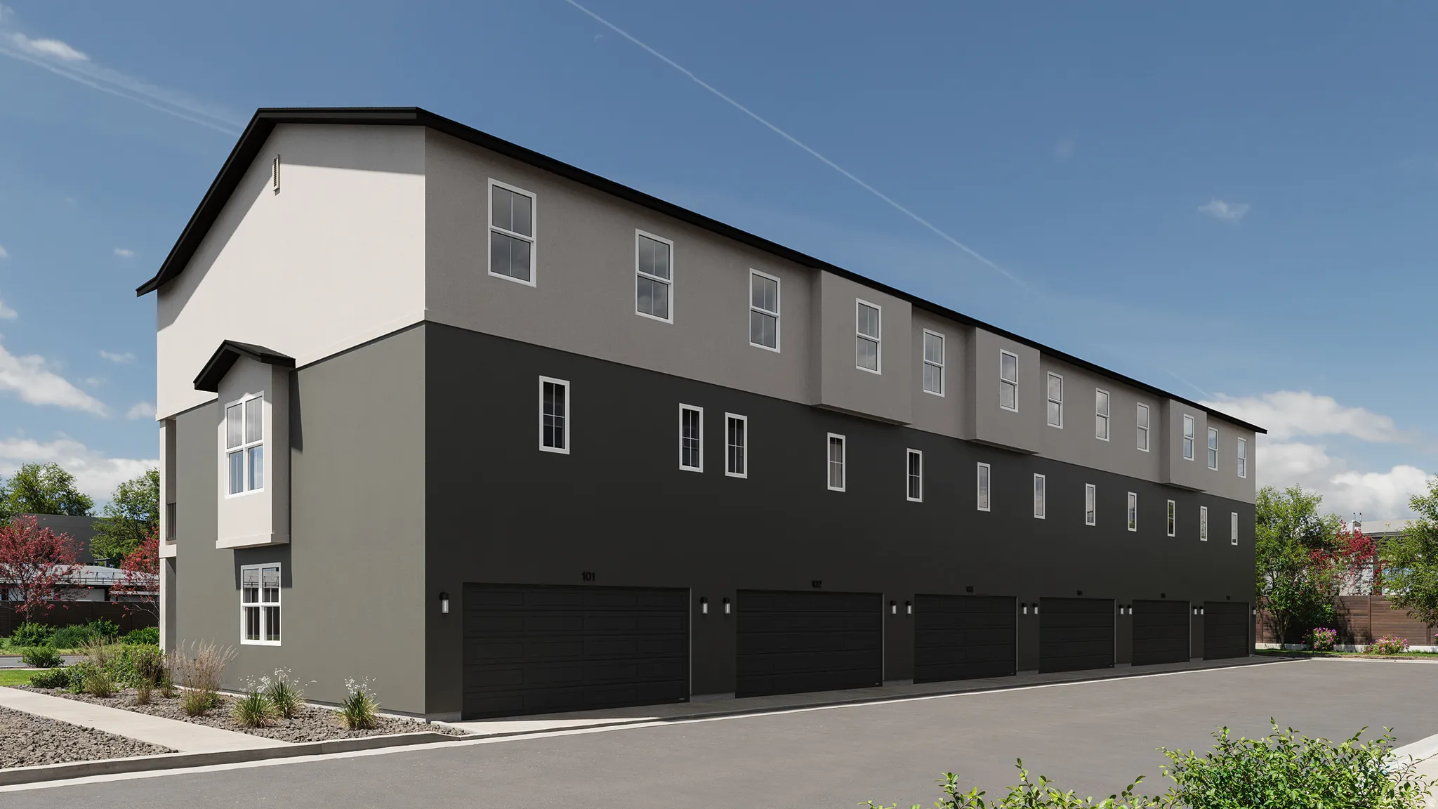 Multi-story townhome building featuring a two-tone exterior, multiple windows, and a series of integrated garage doors