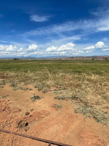 Expansive open land featuring distant mountainous terrain under a blue sky with clouds