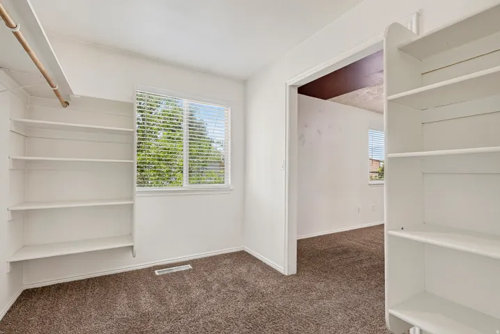 Built-in shelving, white walls, and brown carpet flooring