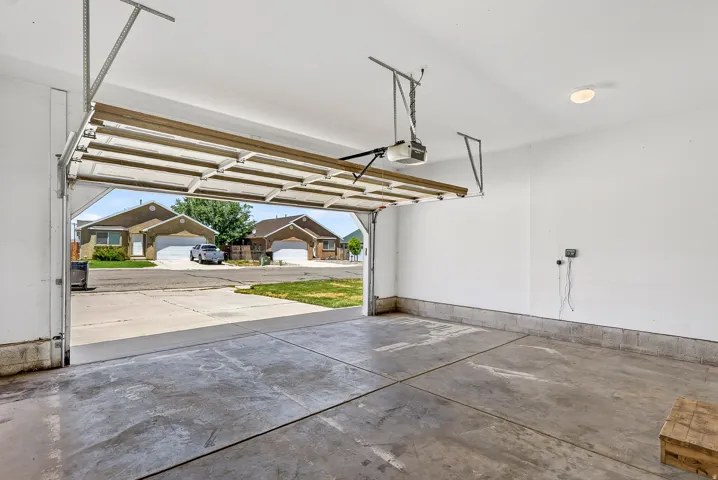 Spacious garage with concrete flooring, automatic garage door opener, and integrated ceiling light fixture