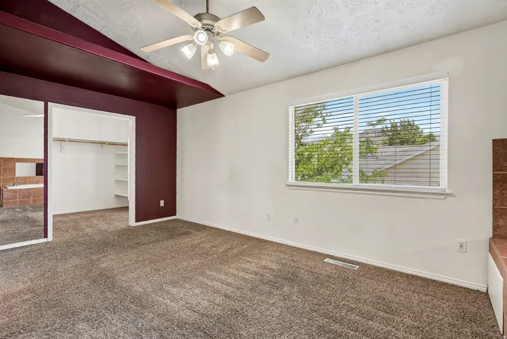 Spacious room featuring carpet flooring, a ceiling fan with integrated lighting, and a window with horizontal blinds