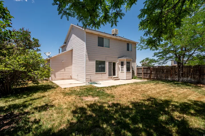 Rear exterior featuring siding, bay window, concrete patio, and fenced perimeter