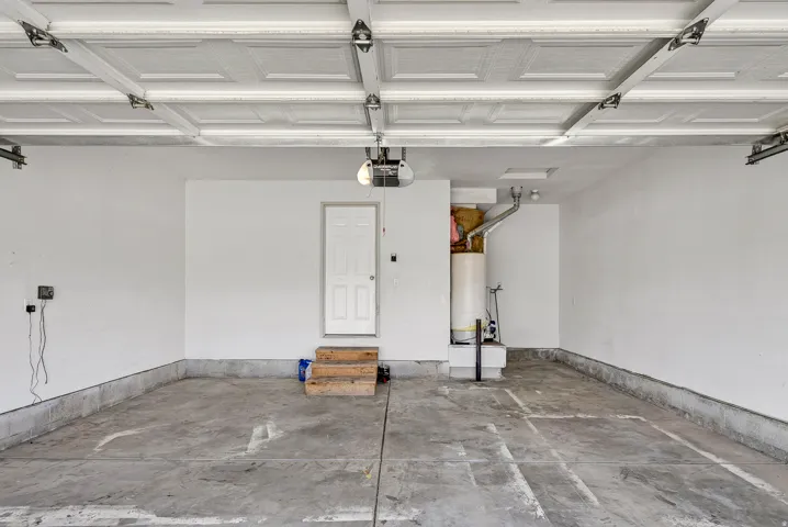 Concrete flooring with a white painted wall finish and a prominent water heater installation