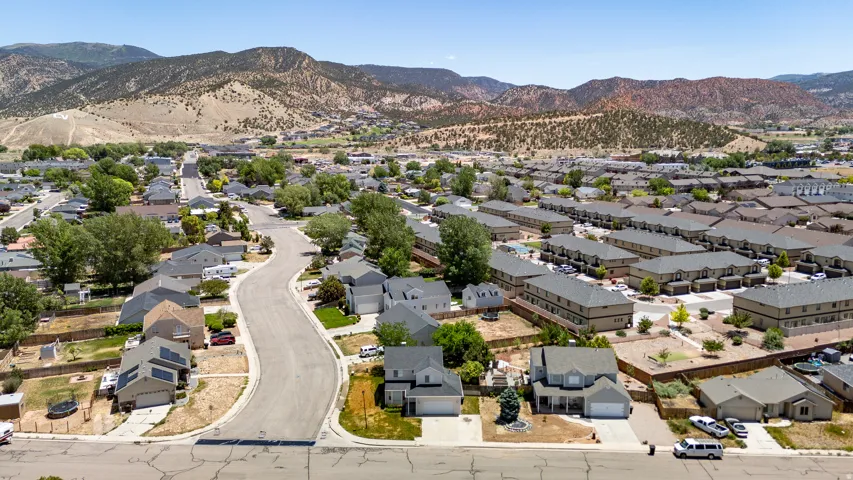 Residential neighborhood with paved streets and mature trees, set against a backdrop of mountains