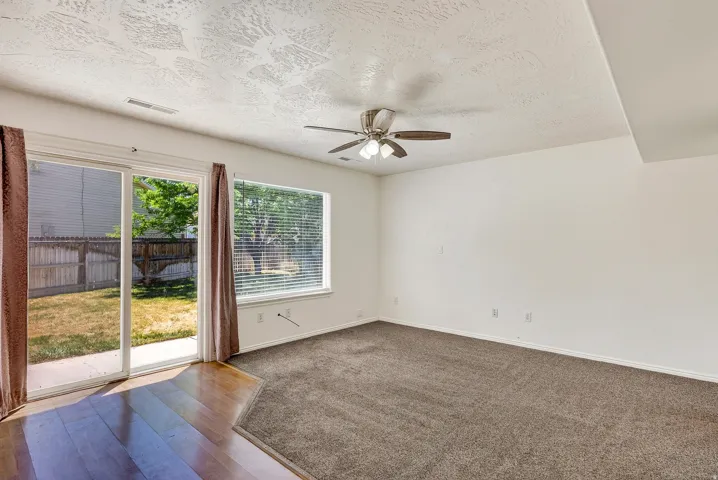 Spacious room featuring a ceiling fan, sliding glass door, and a large window with blinds
