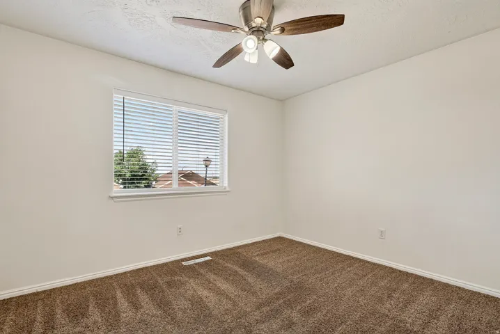 Wall-to-wall carpeting, a window with horizontal blinds, and a ceiling fan with integrated lighting