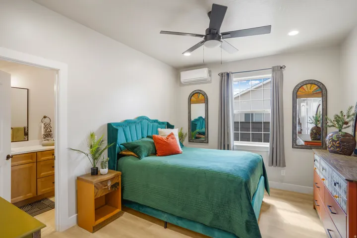 Recessed lighting, ceiling fan, wood-finish flooring, single window, and an attached bathroom with a wood-finish vanity and rectangular mirror